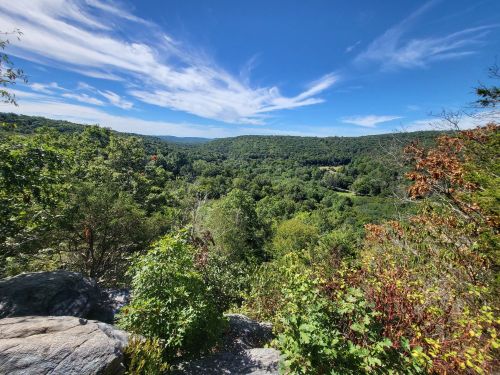 A scenic view of lush green hills under a bright blue sky with wispy clouds.