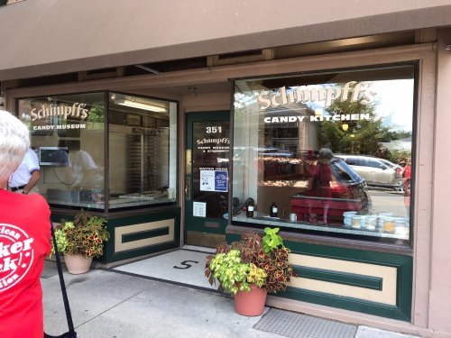 Exterior of Schimpff's Candy Kitchen, featuring large windows displaying candy and a sign for the candy museum.