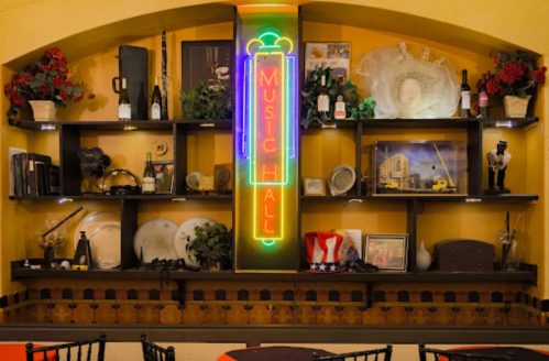 A vibrant wall display featuring a neon "Music Hall" sign, shelves with decor, and various vintage items.