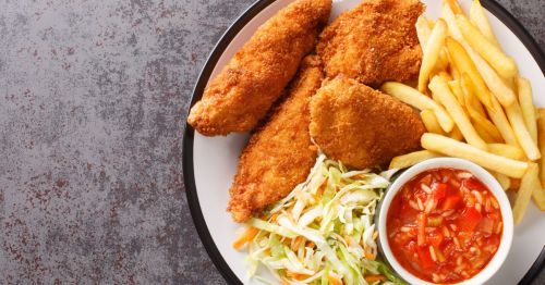 A plate of Barberton or Serbian fried chicken with tomato rice, fries, and coleslaw