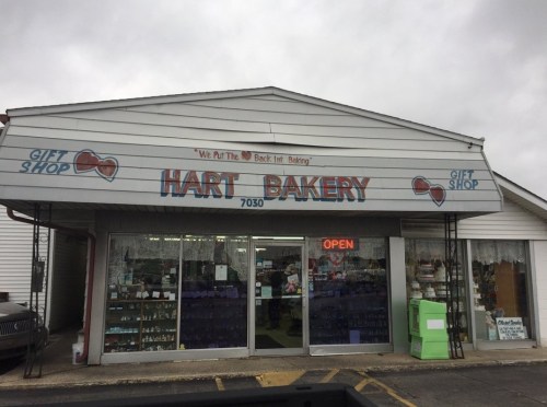 A storefront with a sign reading "Hart Bakery" and "Gift Shop," featuring an open sign and decorative window displays.