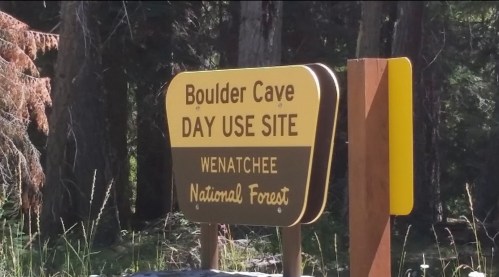 Sign for Boulder Cave Day Use Site in Wenatchee National Forest, surrounded by trees and natural scenery.