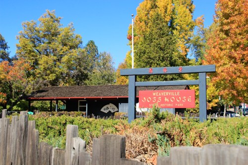 Sign for Weaverville Joss House in a historic park, surrounded by colorful autumn trees and a wooden fence.