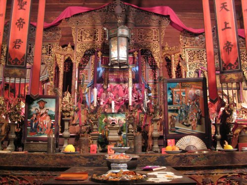 A vibrant altar adorned with intricate carvings, colorful banners, and offerings, showcasing traditional cultural elements.