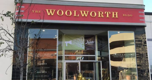Exterior of The Woolworth Building, featuring large windows and a red sign with the name prominently displayed.