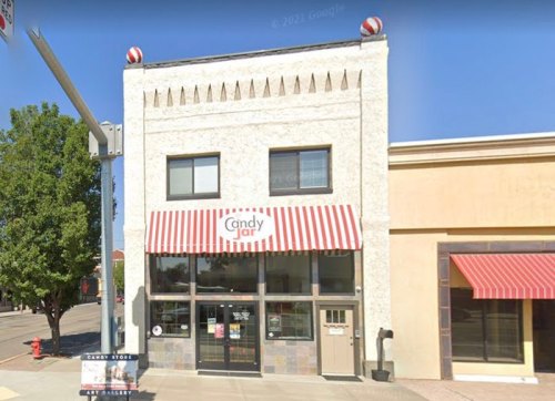 A storefront of "Candy Jar" featuring a striped awning and decorative elements on the facade.