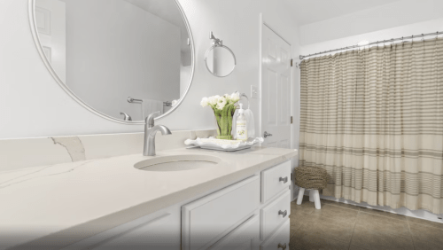 A modern bathroom featuring a round mirror, a sink with a countertop, and a shower curtain with a striped pattern.