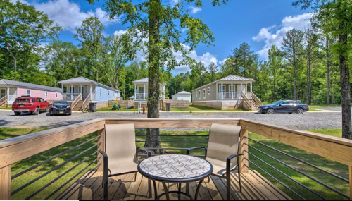 A view from a deck with two chairs and a table, overlooking mobile homes and a clear blue sky.