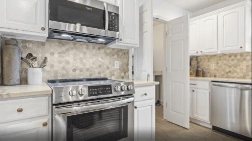 Modern kitchen featuring white cabinets, stainless steel appliances, and a hexagonal tile backsplash.