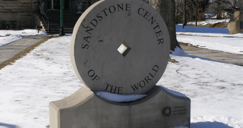 A large stone monument reading "Sandstone Center of the World," surrounded by snow and trees.