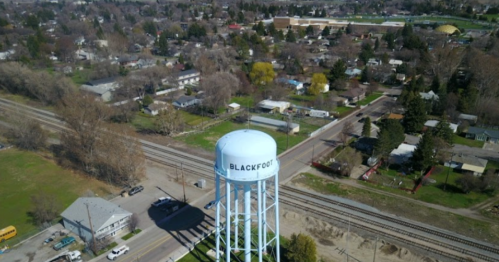 Aerial view of a water tower labeled "BLACKFOOT" surrounded by residential areas and railway tracks.