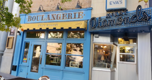 A charming bakery with blue doors and a sign reading "Boulangerie" next to a jewelry store named "McKay Diamonds."