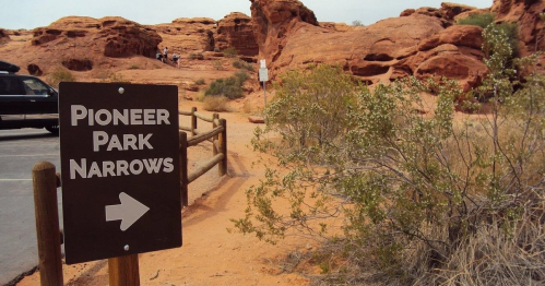 Sign for Pioneer Park Narrows with red rock formations and desert vegetation in the background.