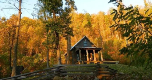 A cozy cabin surrounded by vibrant autumn trees, bathed in warm golden sunlight.