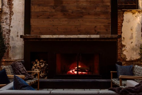 Cozy outdoor fireplace with a warm glow, surrounded by rustic walls and comfortable seating.