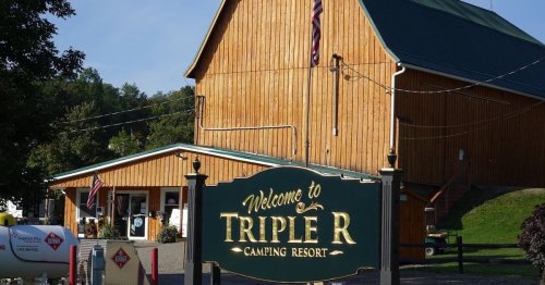 A wooden building with a green roof and a sign reading "Welcome to Triple R Camping Resort" in front.