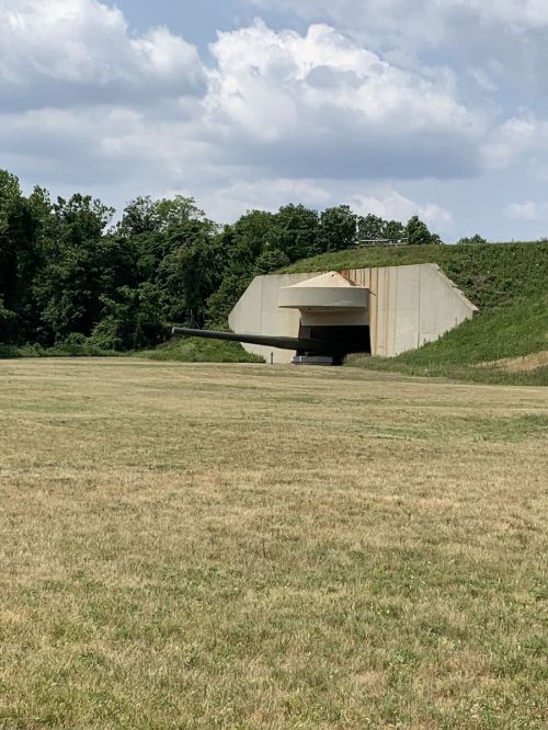 A large concrete bunker with a sloped roof, set in a grassy field under a partly cloudy sky.
