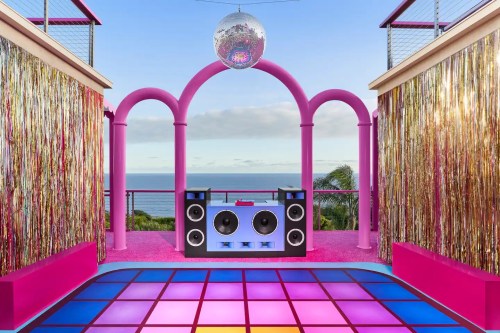 A vibrant outdoor party space with a disco ball, colorful lights, and a scenic ocean view in the background.