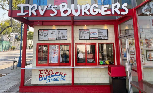A colorful burger stand with a sign reading "Irv's Burgers" and a menu displayed on the wall.