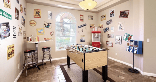 A game room featuring a foosball table, retro decor, and a popcorn machine, with posters on the walls.