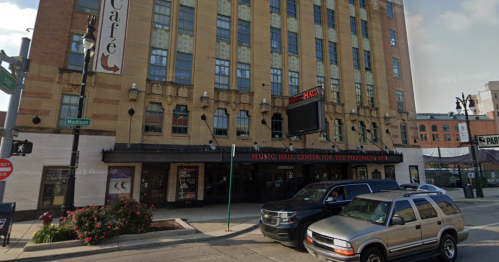 Exterior view of the Music Hall Center for the Performing Arts, featuring a marquee and parked cars in front.