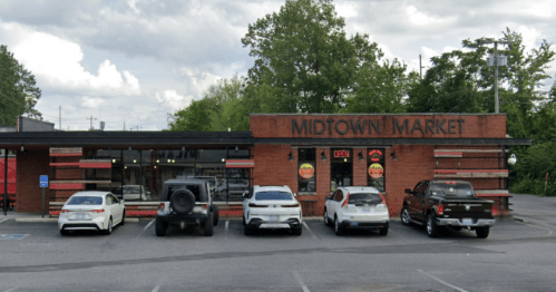 Exterior view of Midtown Market, featuring a brick facade and several parked cars in front.