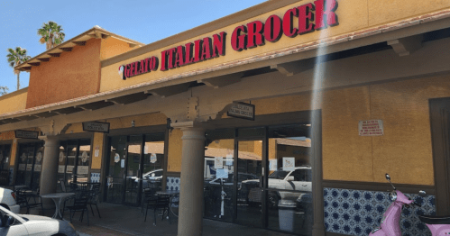 Exterior of a gelato shop with "Gelato Italian Grocer" sign, featuring outdoor seating and a colorful tiled facade.