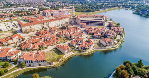 Aerial view of a lakeside community with red-roofed buildings and landscaped areas.