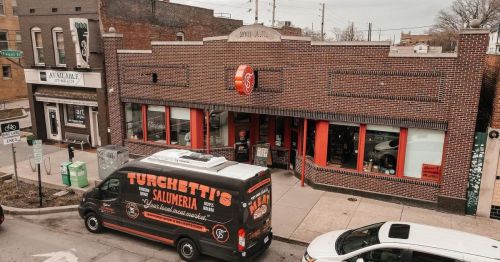 A brick building with a sign for Turchetti's Salumeria, featuring a food truck parked outside.
