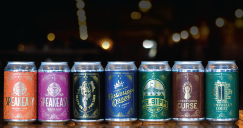 A lineup of colorful craft beer cans on a wooden surface, featuring various fruity sour labels and designs.