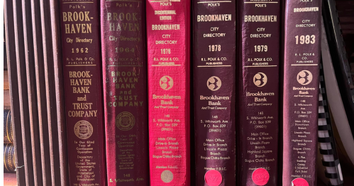 A row of vintage Brookhaven city directories from 1962, 1964, 1976, 1978, and 1983 on a shelf.
