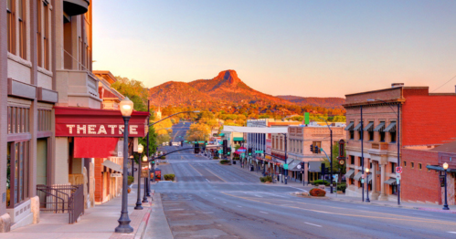A quiet street scene at sunset, featuring a theater and a mountain in the background.