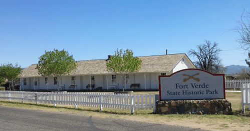 A historic building at Fort Verde State Historic Park, featuring a white exterior and a sign in front.