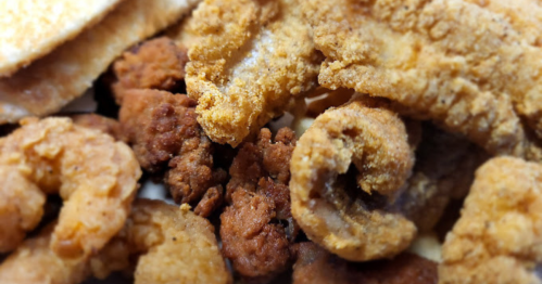 A close-up of a plate featuring various fried seafood, including shrimp and fish fillets.