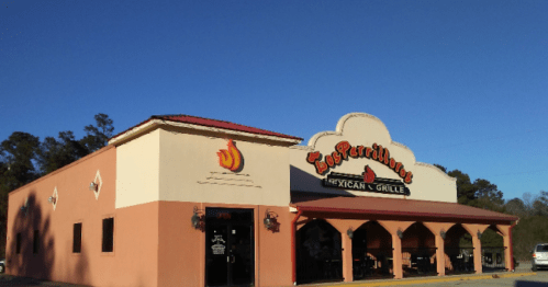 Exterior of a Mexican restaurant with a colorful sign, arched windows, and a clear blue sky in the background.