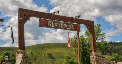 Sign for "Hari Ranch" with a heart design, set against a backdrop of green hills and a cloudy sky.
