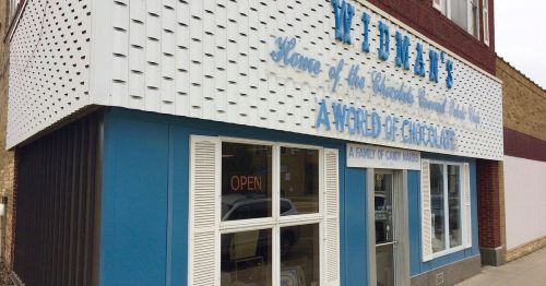 Exterior of Widman's, a candy store with blue and white signage, featuring "Home of the World's Finest Chocolates."