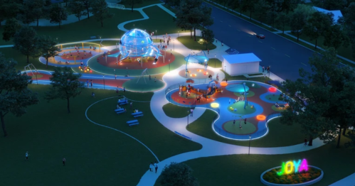 Aerial view of a vibrant, illuminated park at night with playgrounds, walking paths, and colorful light displays.