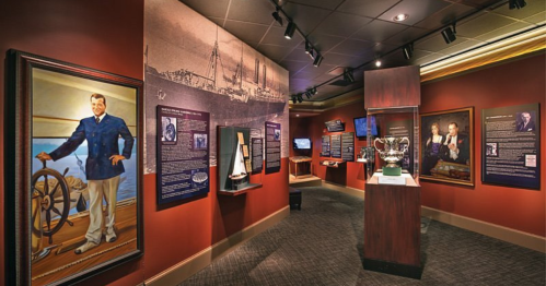 A museum exhibit featuring portraits, historical displays, and maritime artifacts in a warmly lit room.