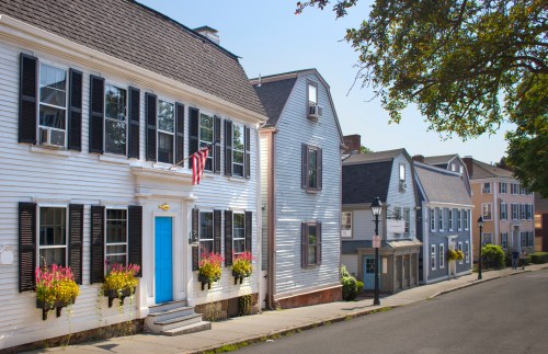 Charming street lined with historic homes, featuring white facades, black shutters, and colorful flower boxes.