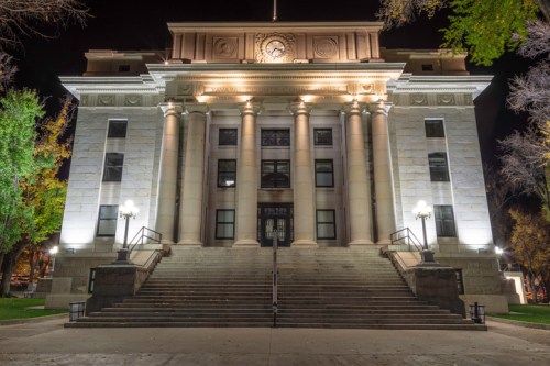 Historic building illuminated at night, featuring grand columns and a staircase leading to the entrance.