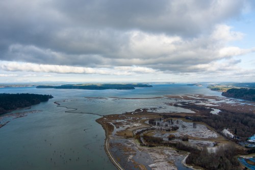 Aerial view of a coastal landscape with water, islands, and cloudy skies.