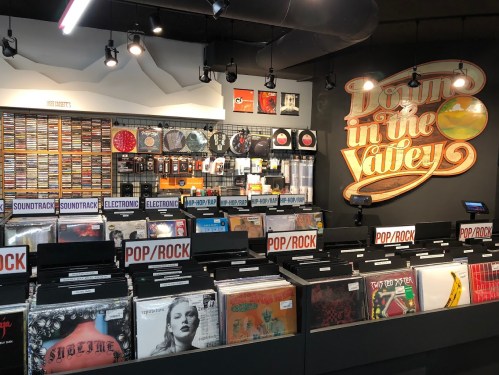 A vibrant record store display featuring various vinyl records and a colorful sign reading "Down in the Valley."