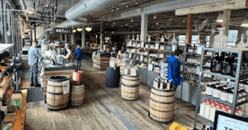 A spacious retail store with wooden barrels and shelves filled with various products, bustling with shoppers.