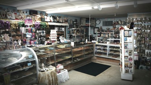 A cozy shop interior filled with various collectibles, displays, and a glass case showcasing sweets and treats.