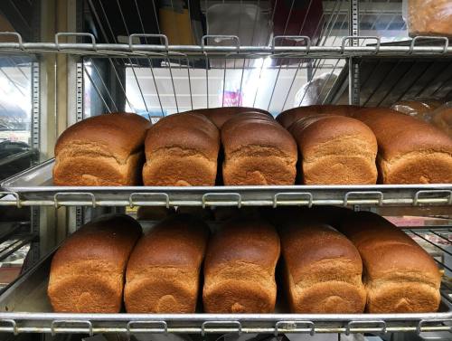 Freshly baked loaves of bread arranged on metal racks in a bakery.