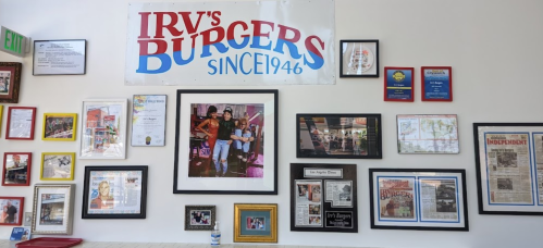 A wall display at Irv's Burgers featuring a banner, framed photos, and newspaper clippings celebrating its history since 1946.