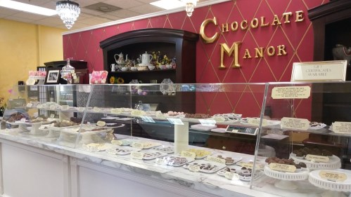 A display case filled with various chocolates and confections in a cozy shop, with elegant decor and a warm atmosphere.