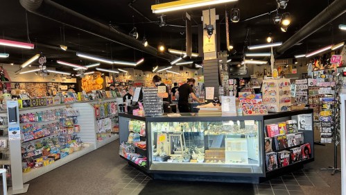 A vibrant store interior with a central display counter, shelves filled with various items, and customers browsing.