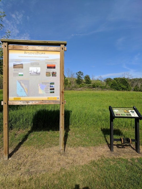 Information signs in a grassy area, with trees and blue sky in the background.
